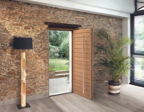 porte d'entrée en bois moderne avec une barre de tirage verticale dans une maison rénovée avec des murs en pierre